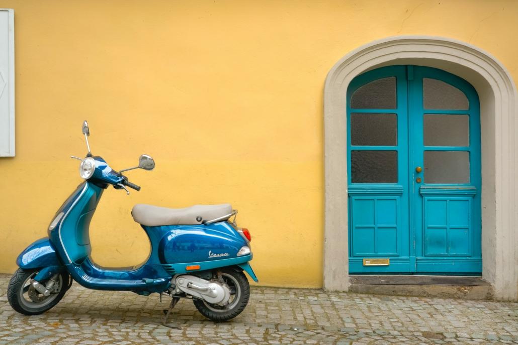 Instituut voor Zakelijke Mediation - Blauwe scooter voor een okergele muur met een blauwe deur