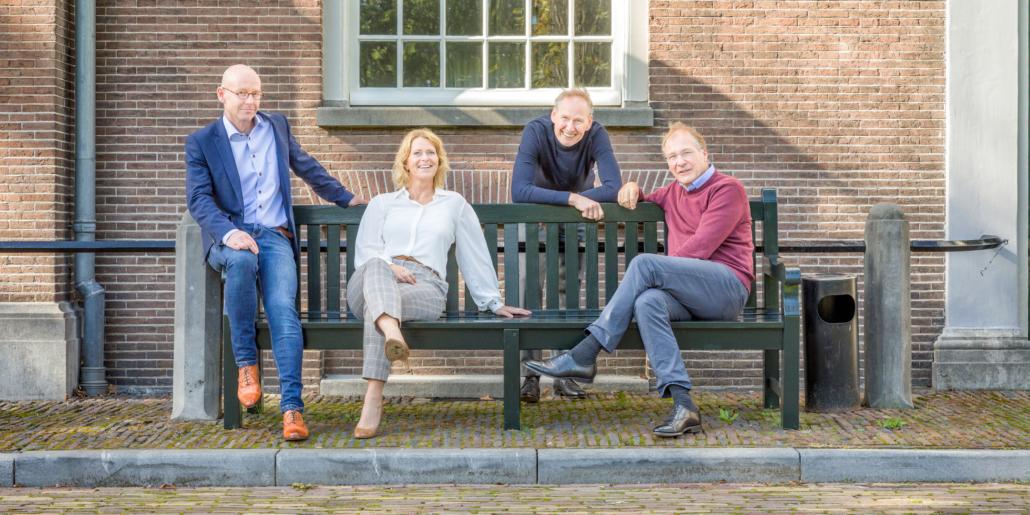 Instituut voor Zakelijke Mediation -team op een houten bank voor een oud gebouw